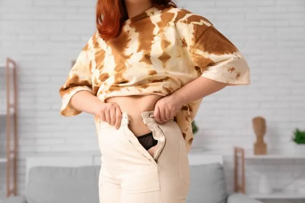 Image of woman trying to do her trousers up after pregnancy weight gain Caversham